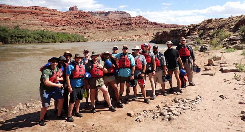 a group of veterans pose by a river on an outward bound trip